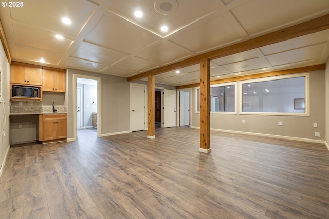 unfurnished living room featuring coffered ceiling, sink, and hardwood / wood-style flooring