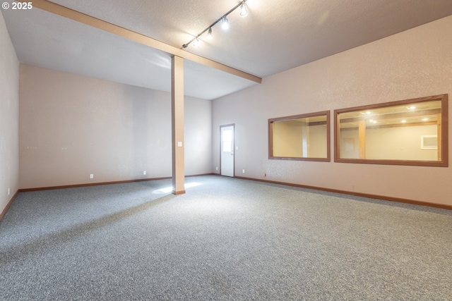 unfurnished room with a textured ceiling, rail lighting, beamed ceiling, and carpet