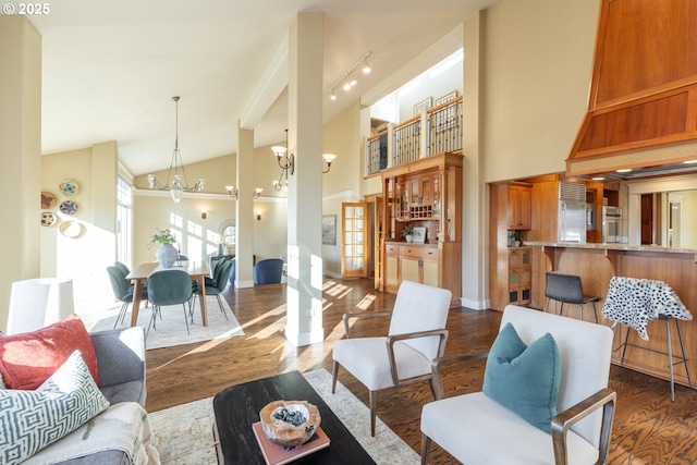 interior space featuring an inviting chandelier, dark hardwood / wood-style flooring, high vaulted ceiling, and track lighting