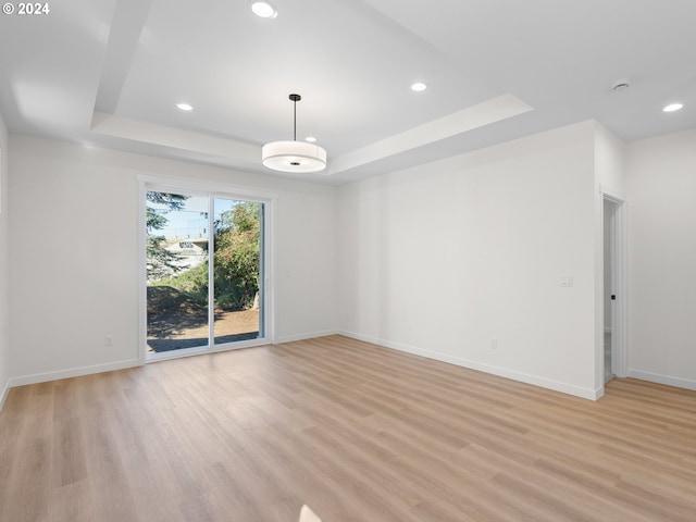 spare room featuring light hardwood / wood-style flooring and a raised ceiling