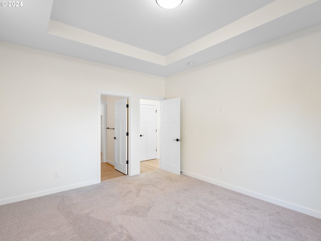 spare room featuring light carpet and a tray ceiling