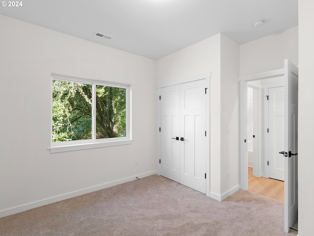 unfurnished bedroom featuring light colored carpet and a closet