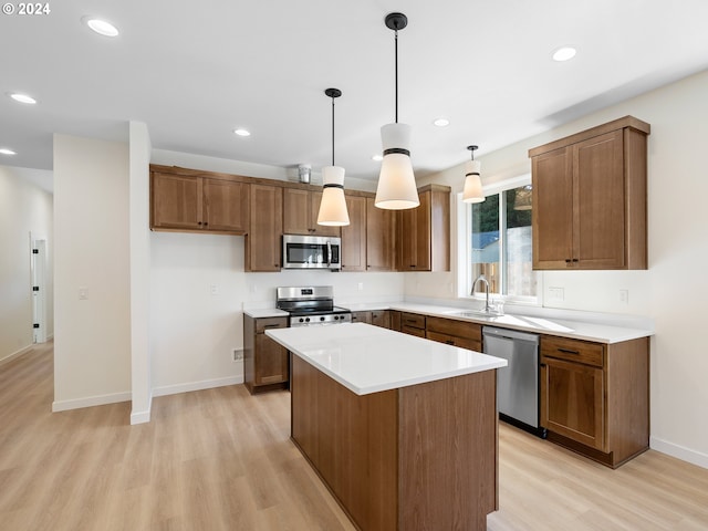 kitchen with sink, light hardwood / wood-style floors, hanging light fixtures, a kitchen island, and appliances with stainless steel finishes