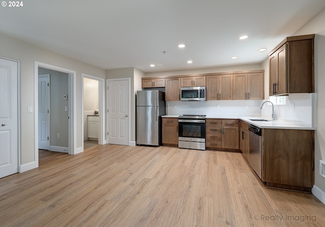 kitchen featuring sink, light hardwood / wood-style flooring, decorative backsplash, and stainless steel appliances