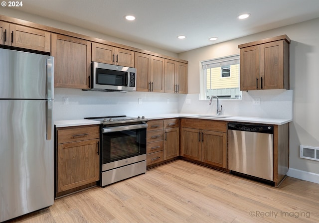 kitchen with sink, stainless steel appliances, and light hardwood / wood-style floors