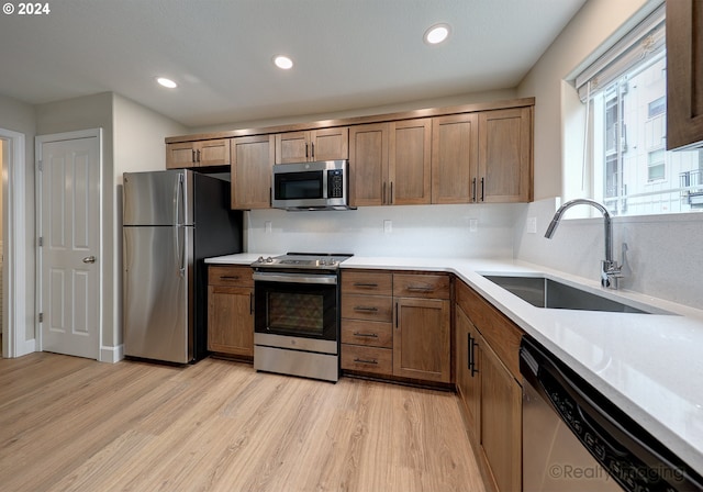 kitchen with light hardwood / wood-style floors, stainless steel appliances, and sink