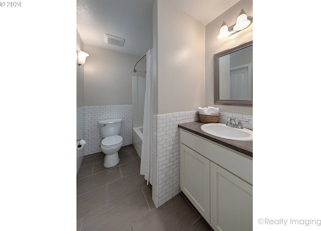 full bathroom featuring tile walls, toilet, vanity, shower / tub combo with curtain, and tile patterned flooring