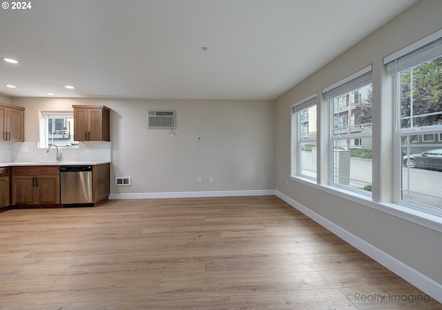 kitchen featuring sink, dishwasher, light hardwood / wood-style flooring, and a healthy amount of sunlight