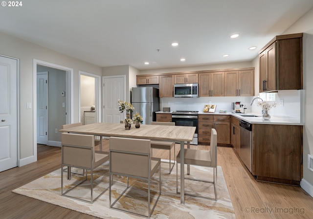 kitchen with a breakfast bar area, stainless steel appliances, sink, a center island, and light wood-type flooring