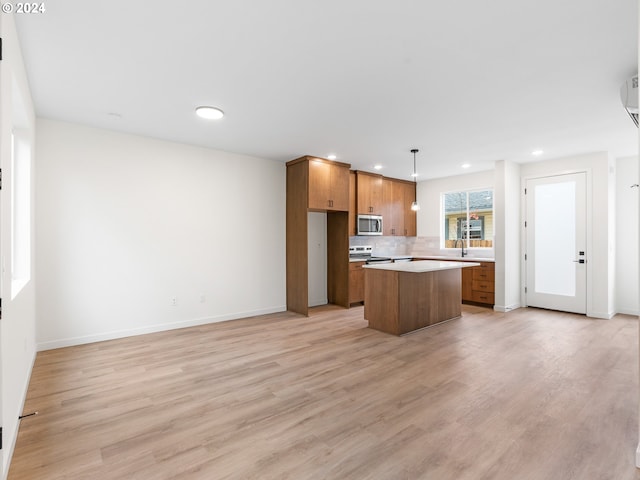 kitchen with sink, decorative light fixtures, a kitchen island, light hardwood / wood-style floors, and decorative backsplash