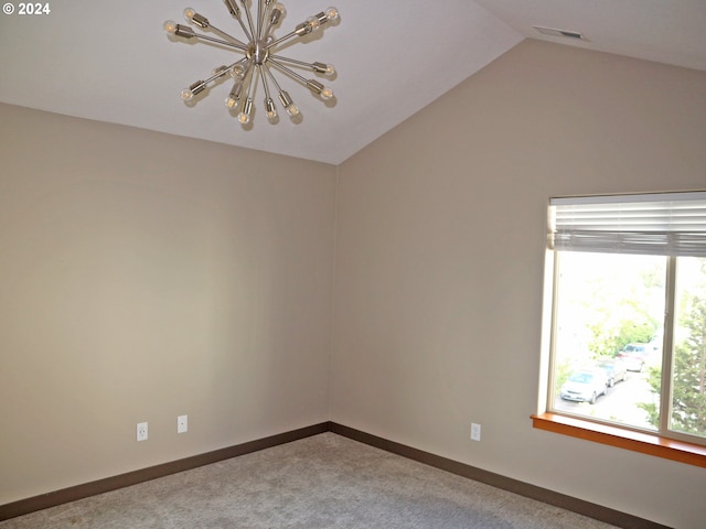 empty room with carpet flooring, vaulted ceiling, and an inviting chandelier