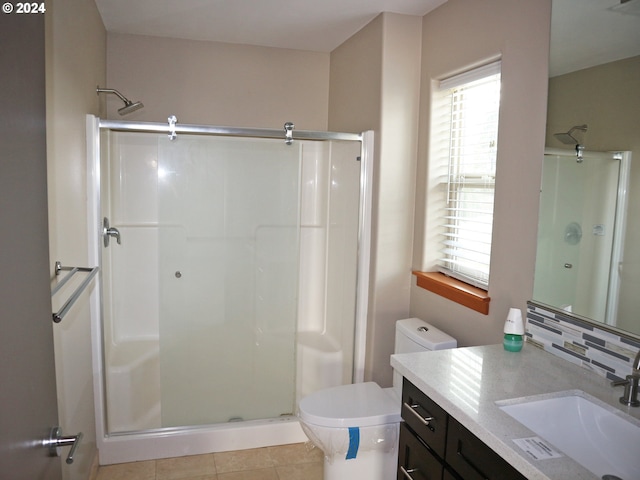 bathroom with decorative backsplash, a shower with door, toilet, vanity, and tile patterned flooring