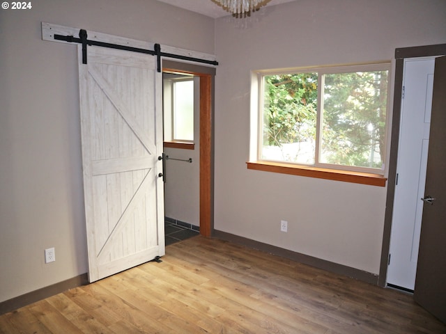 unfurnished bedroom featuring a barn door and hardwood / wood-style flooring