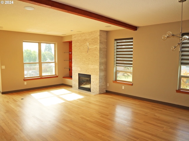 unfurnished living room with light hardwood / wood-style floors, a textured ceiling, beam ceiling, and a fireplace