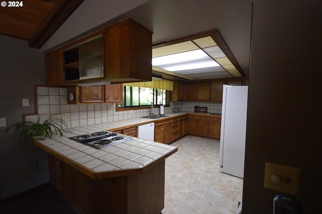 kitchen with kitchen peninsula, white appliances, tile countertops, and sink