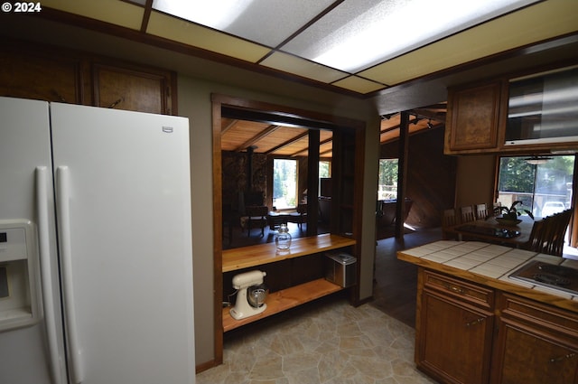 kitchen featuring tile countertops, dark brown cabinets, and white refrigerator with ice dispenser