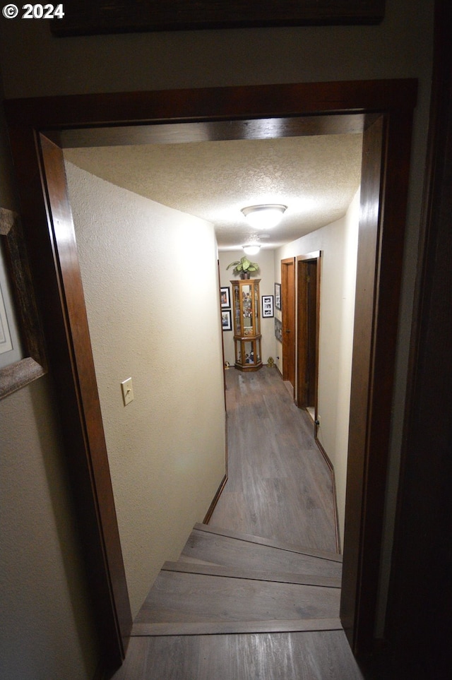 hall with hardwood / wood-style flooring and a textured ceiling