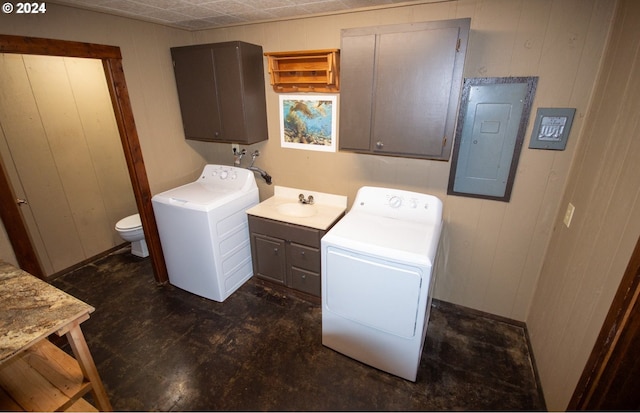 washroom featuring washer and dryer, electric panel, wooden walls, and sink