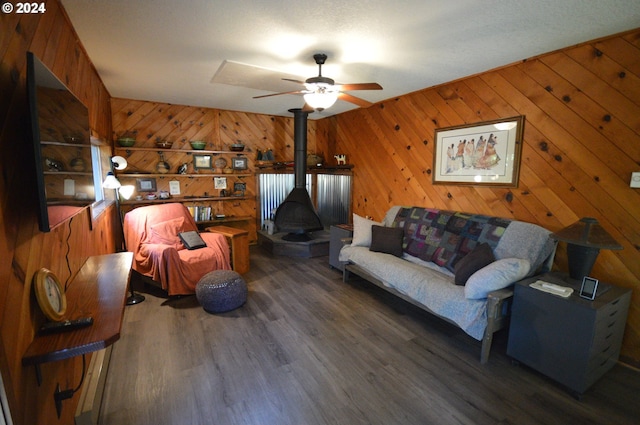 living room featuring dark hardwood / wood-style flooring, ceiling fan, and wood walls