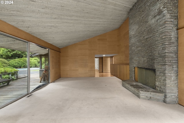 unfurnished living room with wood walls, high vaulted ceiling, and a fireplace