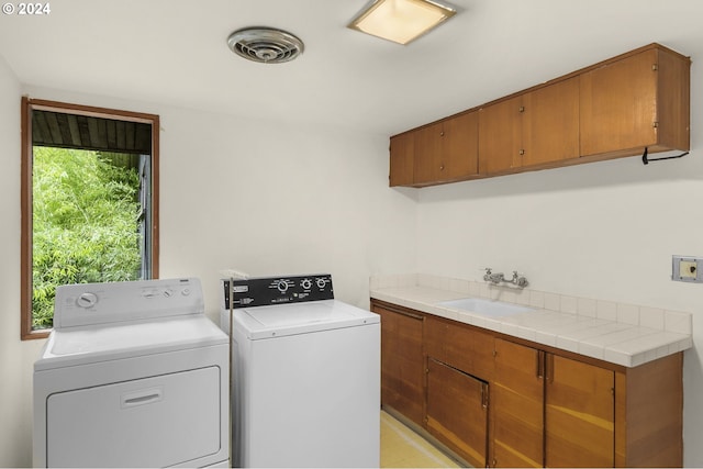 laundry room with washing machine and dryer, cabinets, and sink