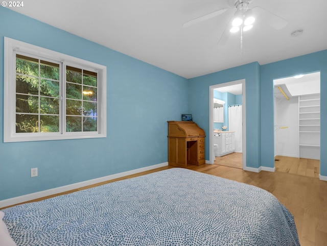 bedroom with light hardwood / wood-style floors, a walk in closet, ensuite bathroom, and ceiling fan