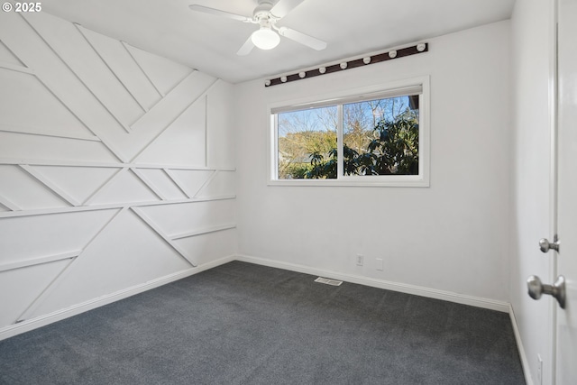 spare room with baseboards, dark colored carpet, visible vents, and a ceiling fan