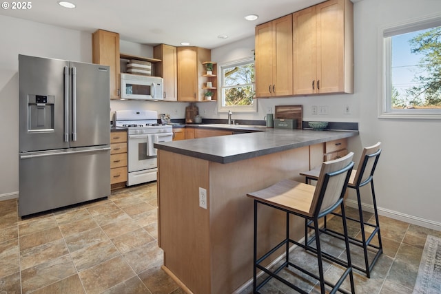 kitchen featuring white appliances, dark countertops, a peninsula, open shelves, and a sink