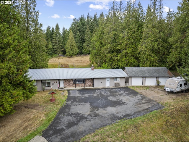 view of front of home with a detached garage, driveway, and metal roof