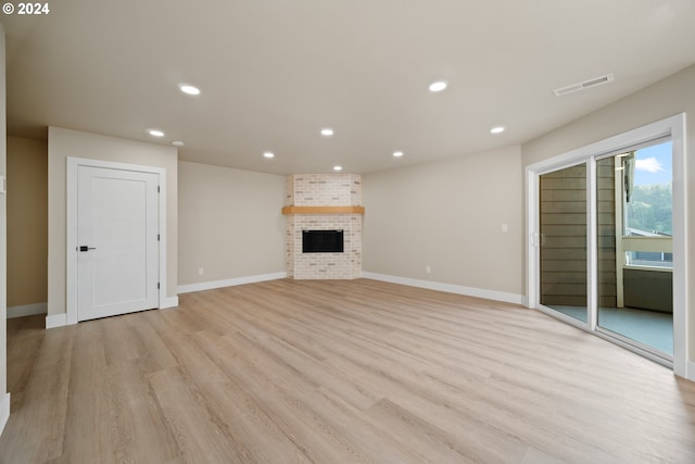 unfurnished living room featuring light hardwood / wood-style floors and a brick fireplace