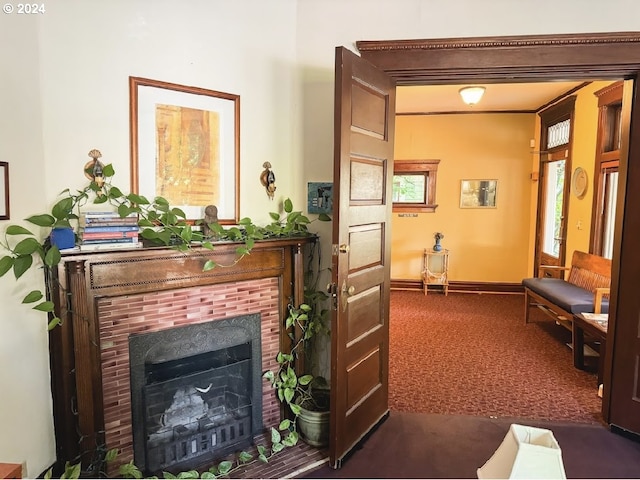 living area featuring a tile fireplace and dark carpet