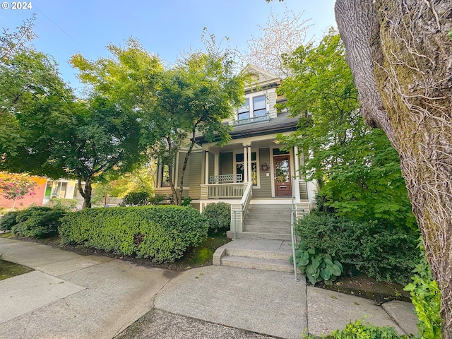 view of property hidden behind natural elements featuring covered porch