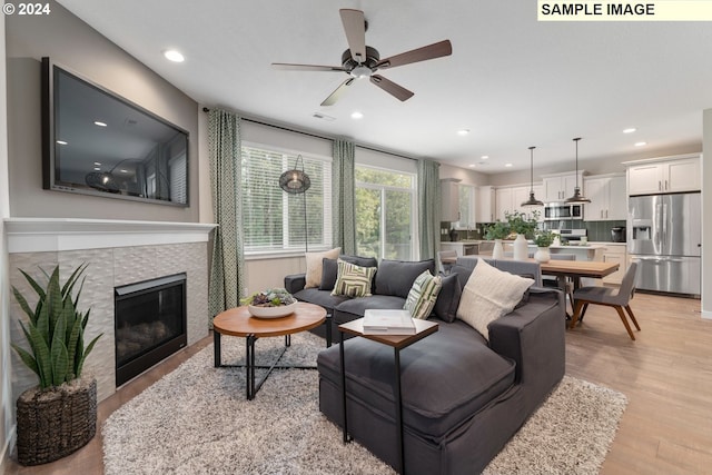 living room featuring a fireplace, ceiling fan, and light hardwood / wood-style flooring