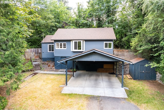 view of front of house with a front yard, a carport, and a storage unit