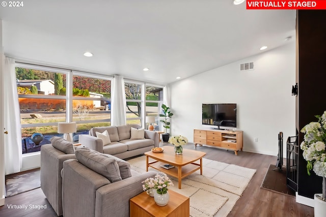 living room featuring dark wood-type flooring, vaulted ceiling, and a wall of windows