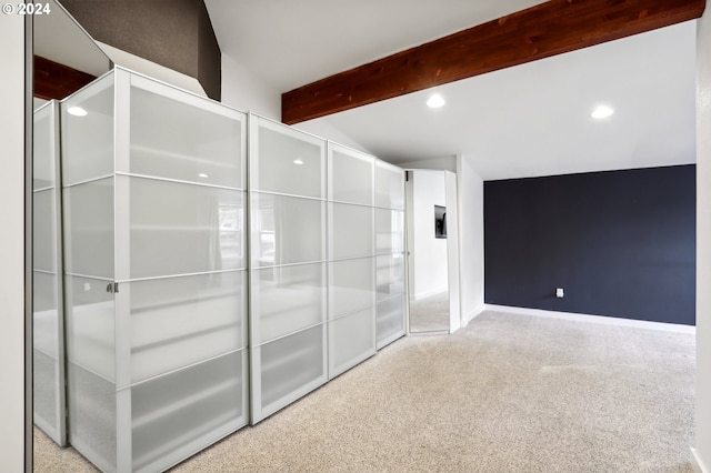 carpeted empty room featuring lofted ceiling with beams