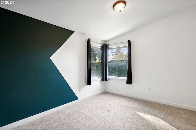 carpeted empty room with lofted ceiling