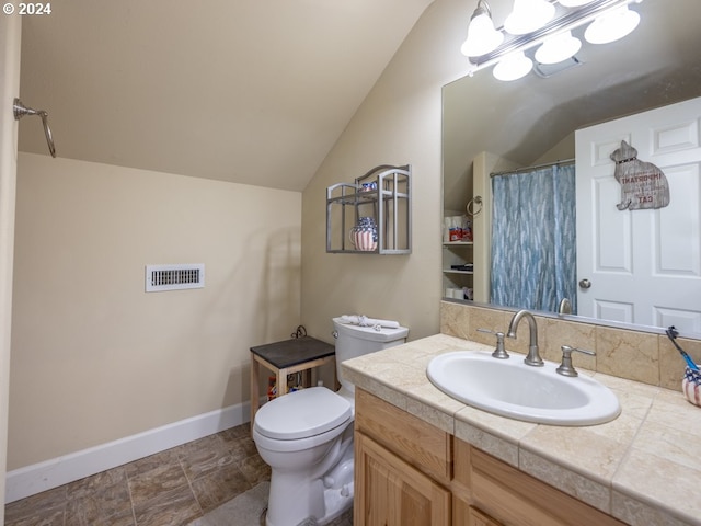 bathroom featuring vanity, toilet, and lofted ceiling