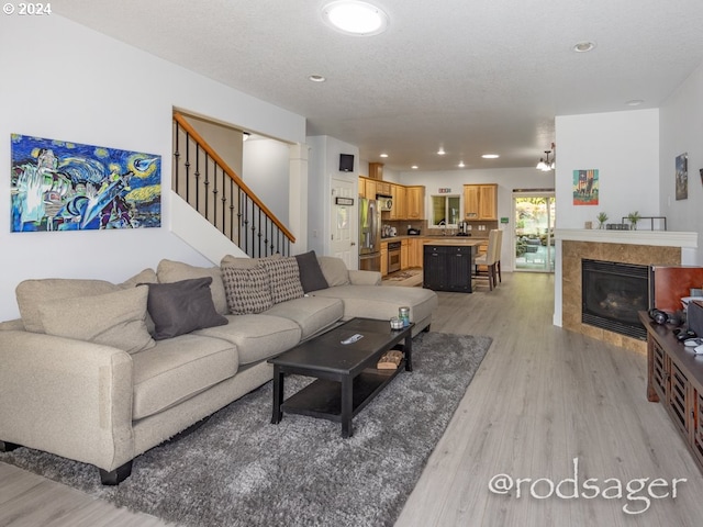 living room featuring light hardwood / wood-style floors, a textured ceiling, and a tile fireplace