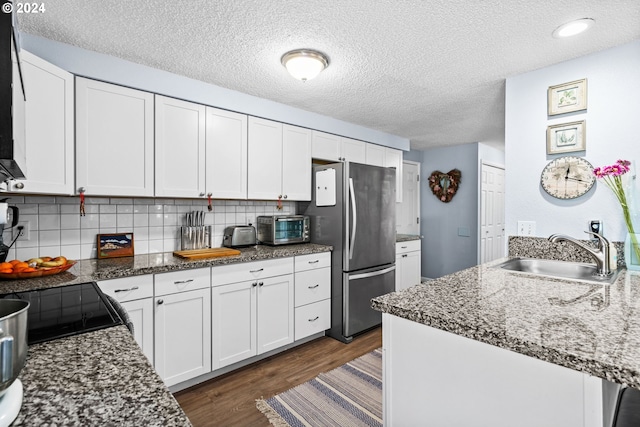 kitchen featuring white cabinets, stainless steel refrigerator, a textured ceiling, sink, and backsplash