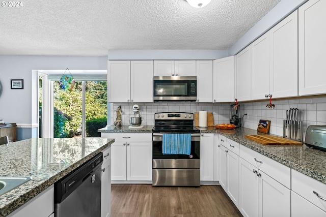 kitchen featuring white cabinets, stainless steel appliances, backsplash, and light stone countertops