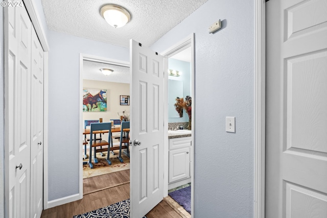 corridor featuring a textured ceiling, sink, and dark hardwood / wood-style floors