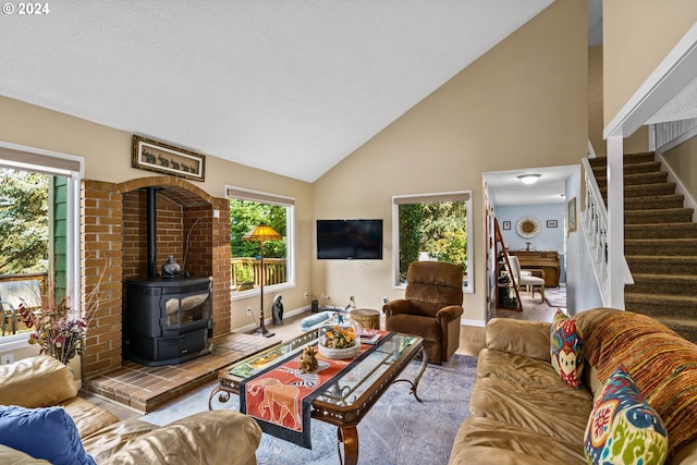 living room featuring high vaulted ceiling, a wealth of natural light, and a wood stove