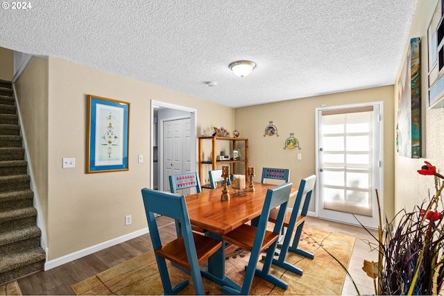 dining space with a textured ceiling and light hardwood / wood-style flooring