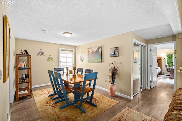 dining space with a textured ceiling and dark hardwood / wood-style flooring