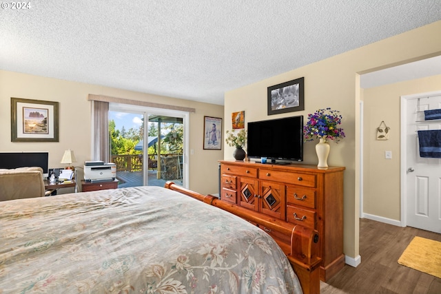 bedroom with a textured ceiling, dark hardwood / wood-style flooring, and access to outside