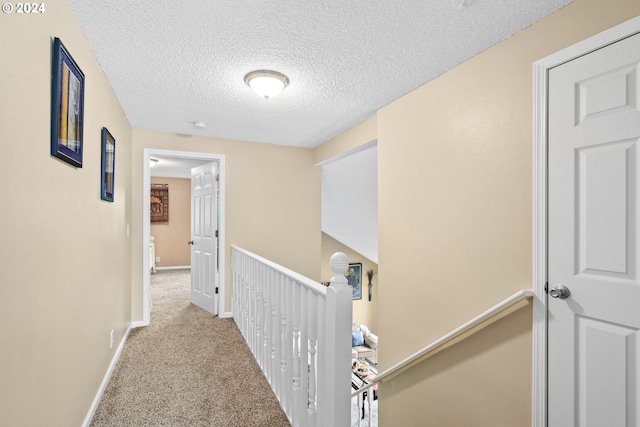 hall with a textured ceiling and light carpet