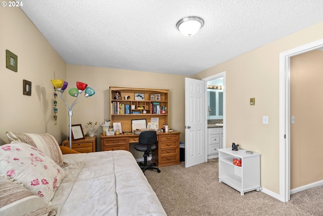 carpeted bedroom with ensuite bath and a textured ceiling