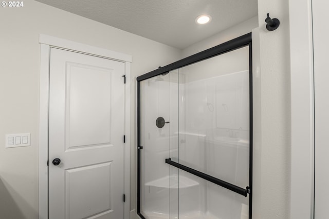 full bathroom with a shower stall, a textured ceiling, and recessed lighting