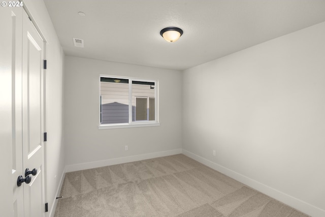 unfurnished room with baseboards, visible vents, and light colored carpet